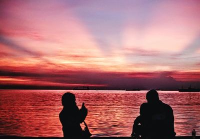 Silhouette man standing by sea against romantic sky at sunset