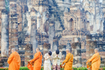 Bride and bridegroom greeting monks against historic temple