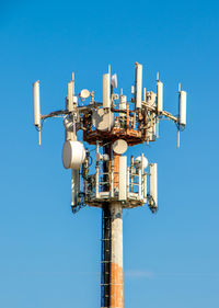 Low angle view of communications tower against clear blue sky