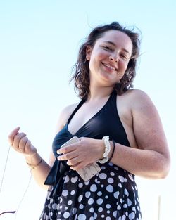 Young woman standing against sky