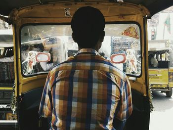 Rear view of man driving auto rickshaw