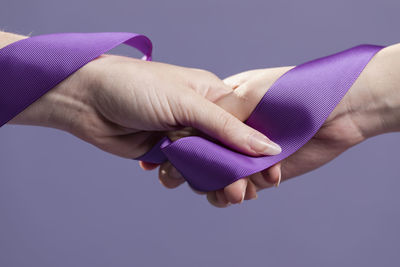 Close-up of hands holding purple over blue background