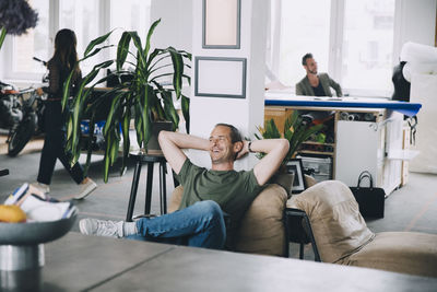 Smiling businessman relaxing with hands behind head in office