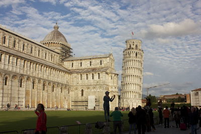 People by pisa cathedral against sky in city