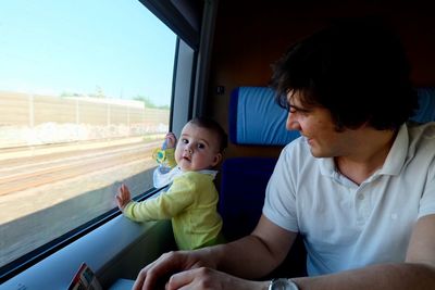 Father and son by glass window in train