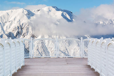 Snow covered railing against snowcapped mountain