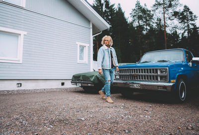 Portrait of man standing on car against building