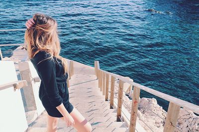 High angle view of beautiful woman standing on steps by sea