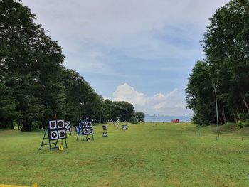 People on field by trees against sky