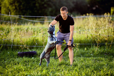 Side view of man with dog on field