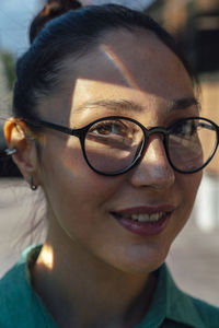 Smiling businesswoman with sunlight on face wearing eyeglasses