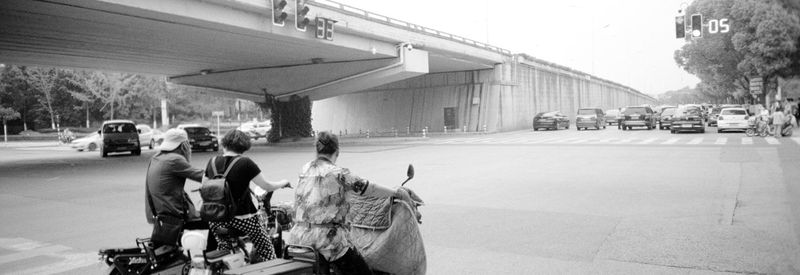 Rear view of people walking on road in city