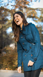 Close-up of smiling young woman against tree