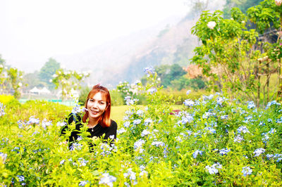 Portrait of smiling young woman with flowers in field