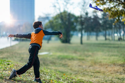 Young boy playing with airplane toy in the park