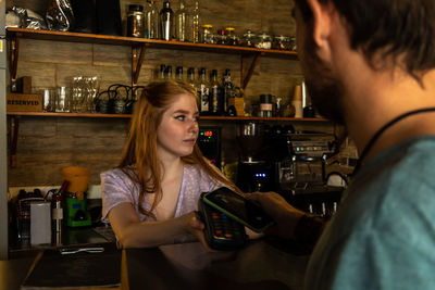 Young man pays for his order at the cafe with his phone