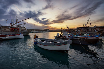 Boats moored at harbor during sunset