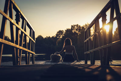 View of dog on railing against sky during sunset