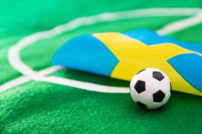 Close-up of small soccer ball with flag on green textile