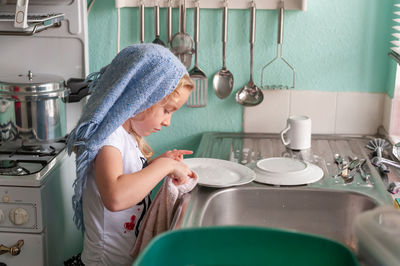 Side view of woman standing in kitchen at home