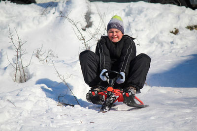 Full length of man sitting on snowy field