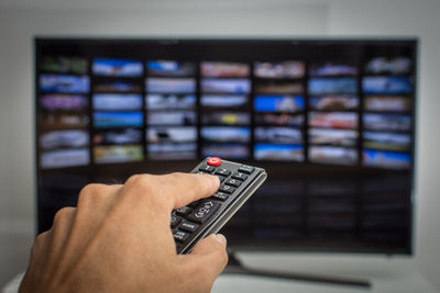 Cropped hand of man holding remote control at home