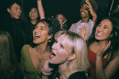 Cheerful multiracial men and women shouting and dancing at nightclub