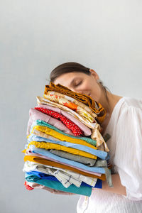 European woman holds a stack of colored clothes in the wardrobe. hand over clothes for recycling