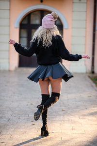 Full length rear view of woman walking on footpath