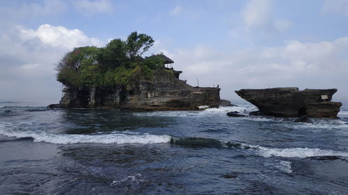 Rock formation on beach against sky