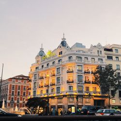 Cars on street by buildings against sky in city