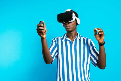 Young man wearing sunglasses standing against blue wall