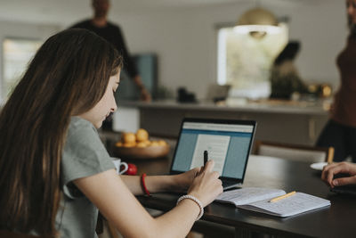 Pre-adolescent girl using laptop while sitting at home