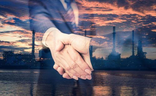 Digital composite image of hands and cityscape against sky