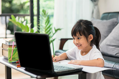 Rear view of siblings sitting on table at home