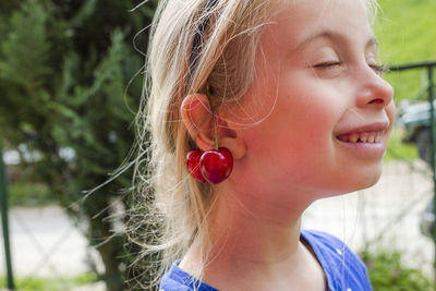 Close-up of cute girl with cherry on ear