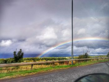 Rainbow over road against sky