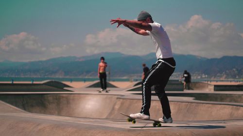 Full length of people skateboarding on mountain against sky