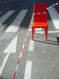 High angle view of orange chair by cordon tape on street