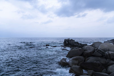 Rocks by sea against sky