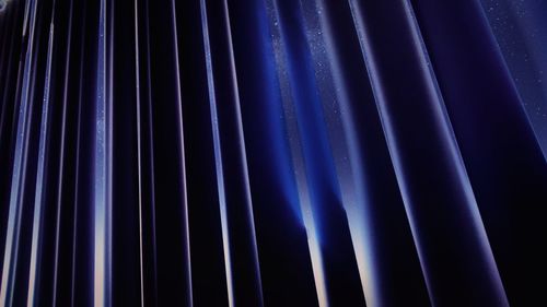 Low angle view of stars seen through dark blue curtain