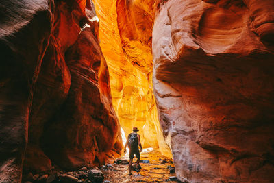 Young man wearing a hat, exploring a slot canyon in kanarra fall, utah