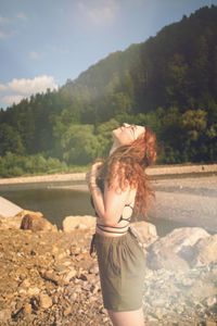 Full length of woman standing by tree against mountain