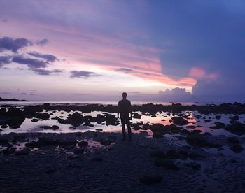 Silhouette man standing on beach against sky during sunset