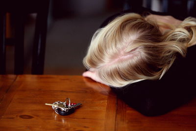 Woman leaning by keys on wooden table at home