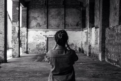 Rear view of woman standing in abandoned building