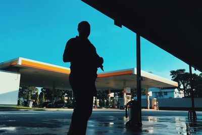 Rear view of silhouette man standing against blue sky