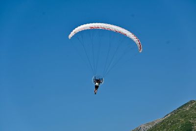 Low angle view of person paragliding against clear blue sky