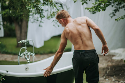 Midsection of shirtless man standing outdoors