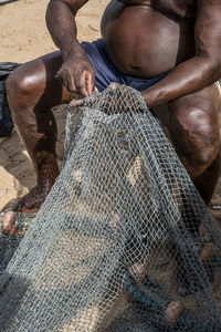 Fisherman repairing fishing net after a period of heavy use.